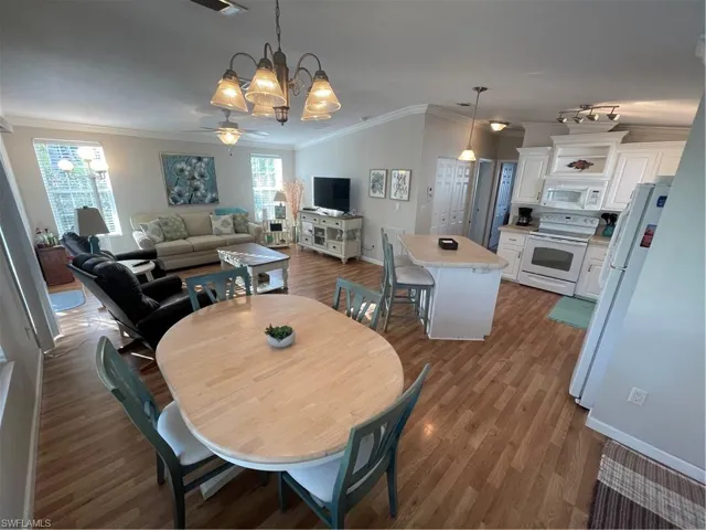 Dining area with ornamental molding, dark wood-style floors, suspended lighting, and ceiling fan