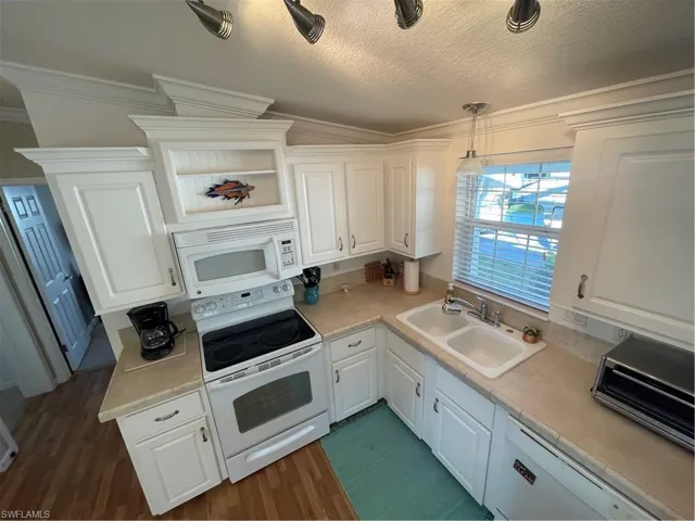 Kitchen with range, white cabinetry, light countertops, dishwasher, and pendant lighting