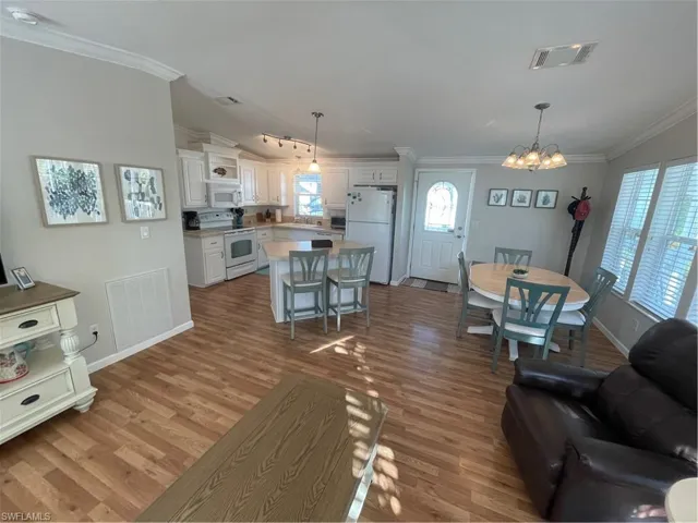 Living room featuring a chandelier, dark wood-style flooring, and ornamental molding