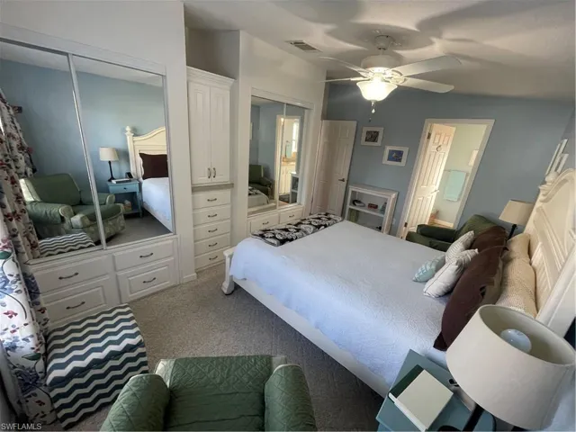 Bedroom with two closets, carpet flooring, ceiling fan, and ensuite bath