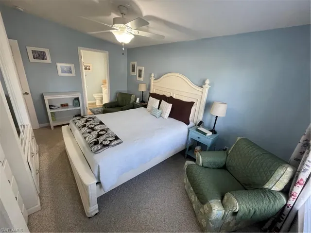 Bedroom featuring ensuite bath, ceiling fan, and carpet flooring