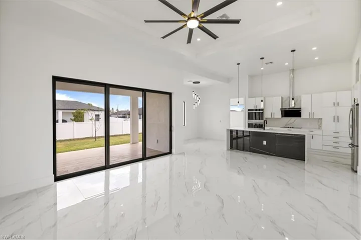 Great Room /Kitchen featuring decorative light fixtures, stainless steel appliances, light countertops, white cabinetry, and modern cabinets