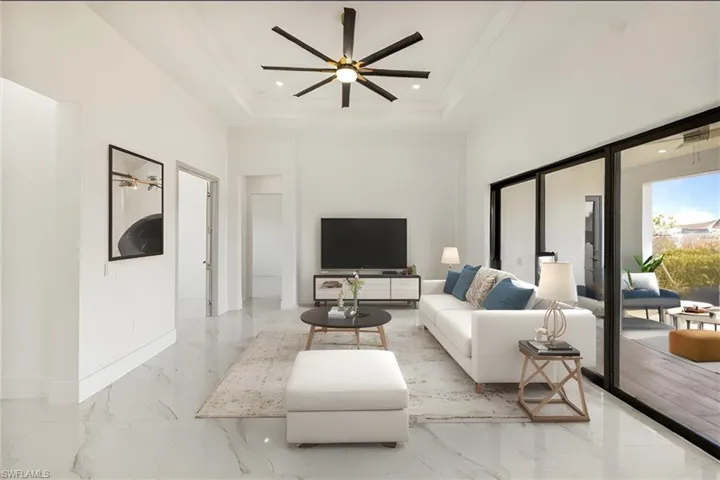 Living area with recessed lighting, a ceiling fan, a towering ceiling, marble finish floor, and a tray ceiling
