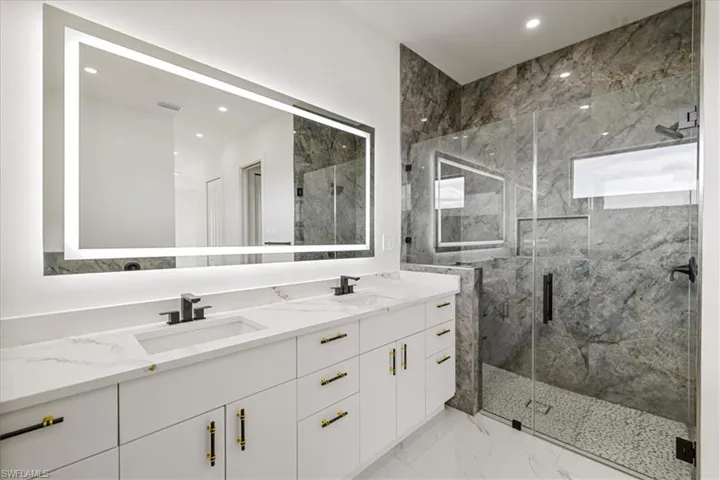 Master Bathroom featuring marble finish floor, a sink, a marble finish shower, and double vanity