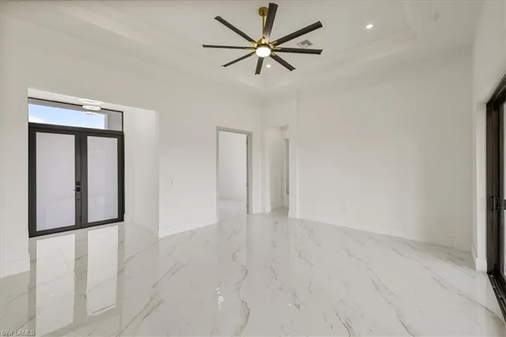 Empty room with french doors, recessed lighting, a raised ceiling, and baseboards