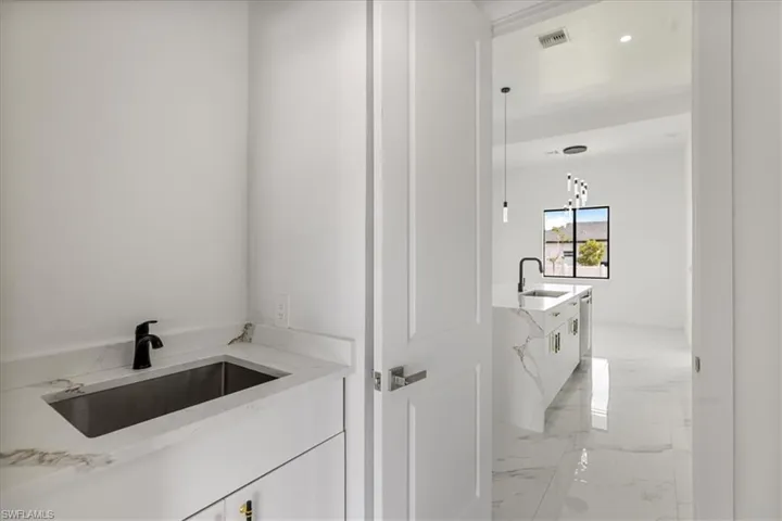 Laundry area with marble finish floor, visible vents, and vanity