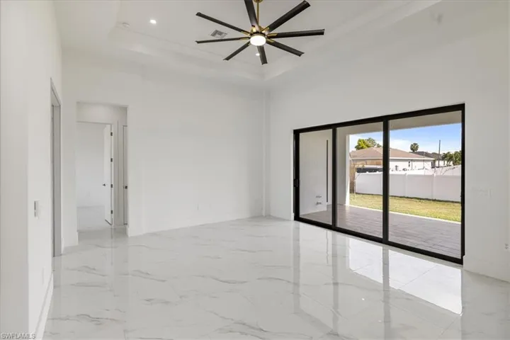 Great room featuring baseboards, marble finish floor, a high ceiling, a tray ceiling, and recessed lighting