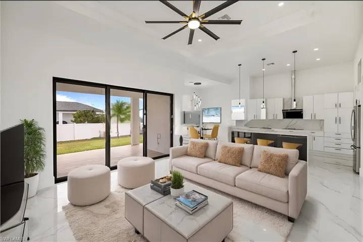 Living area with a tray ceiling, marble finish floor, recessed lighting, a towering ceiling, and ceiling fan