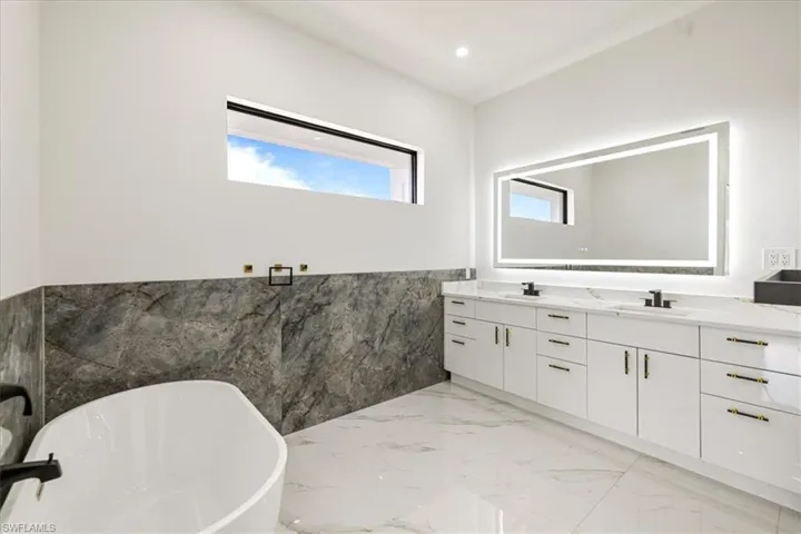 Bathroom featuring marble finish floor, a soaking tub, and a sink