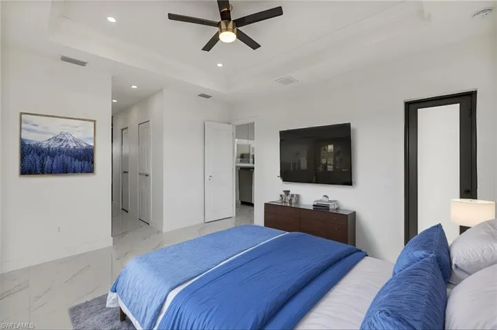 Bedroom with a tray ceiling, marble finish floor, recessed lighting, visible vents, and baseboards