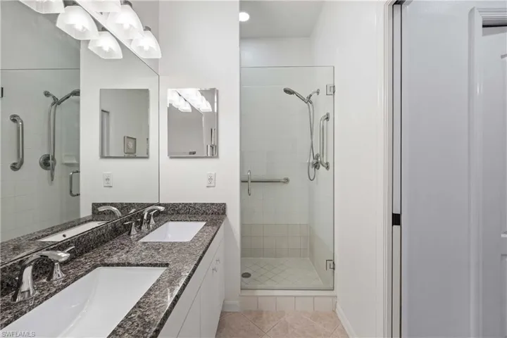 Bathroom featuring tile patterned floors, vanity, and walk in shower