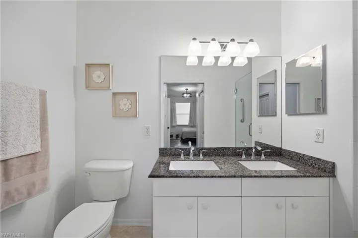 Bathroom with tile patterned flooring, vanity, a shower with door, and toilet