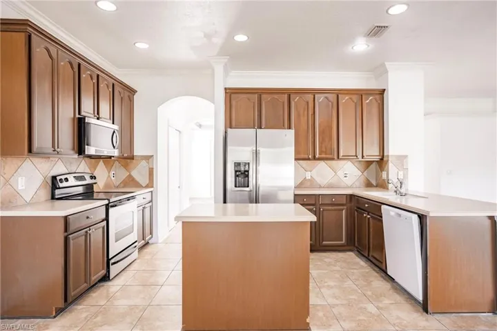 Kitchen with kitchen peninsula, stainless steel appliances, light tile patterned floors, and tasteful backsplash