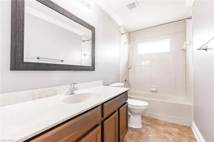 Full bathroom with vanity, crown molding, tiled shower / bath, tile patterned flooring, and toilet
