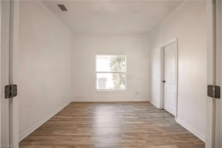 Empty room featuring light wood-type flooring and crown molding