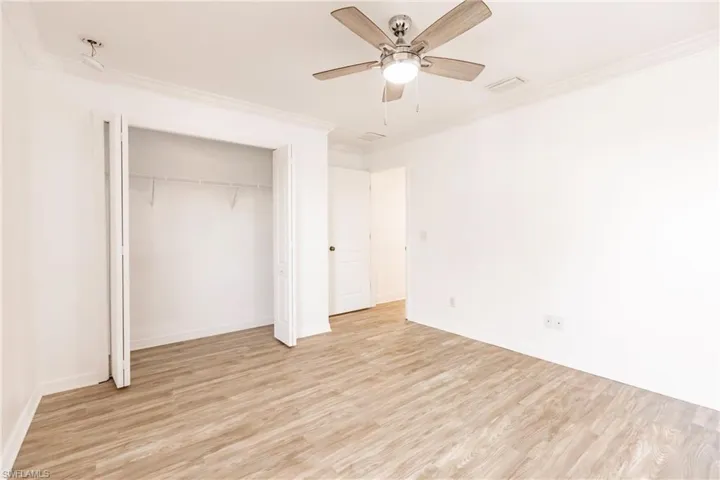 Unfurnished bedroom featuring a closet, ceiling fan, crown molding, and light wood-type flooring