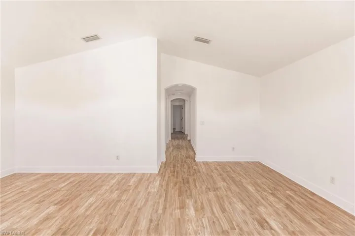 Spare room with light hardwood / wood-style flooring and lofted ceiling