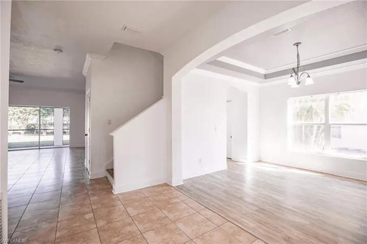 Empty room with ornamental molding, a chandelier, and light wood-type flooring