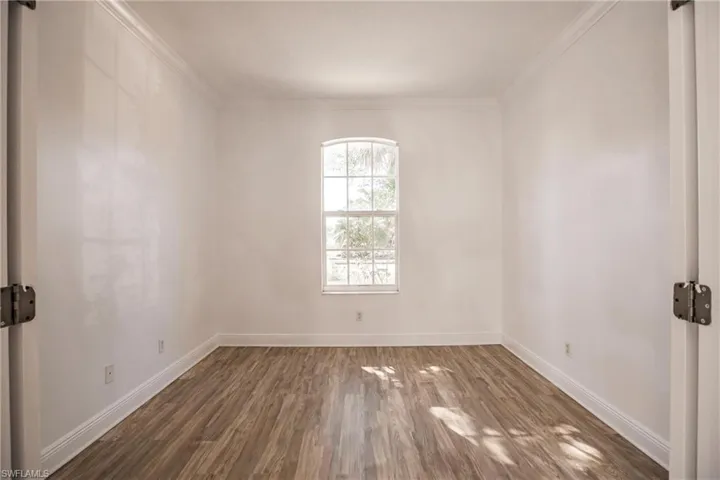 Empty room featuring crown molding and dark wood-type flooring