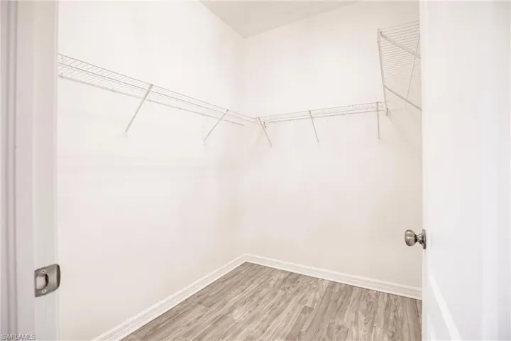 Walk in closet with hardwood / wood-style flooring