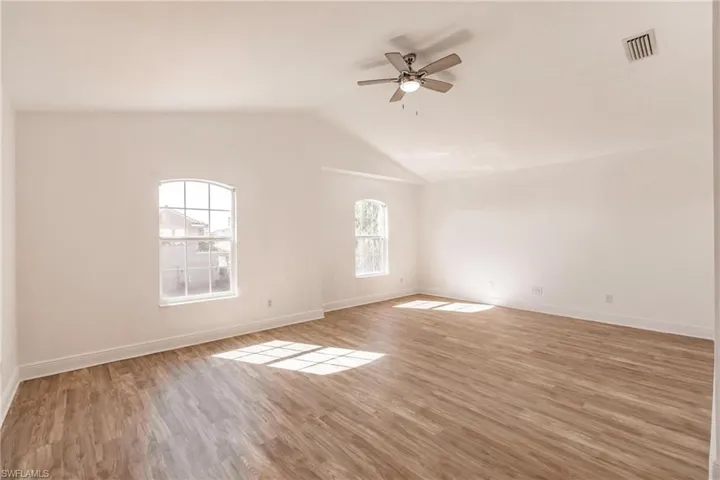Empty room featuring ceiling fan, wood-type flooring, and vaulted ceiling