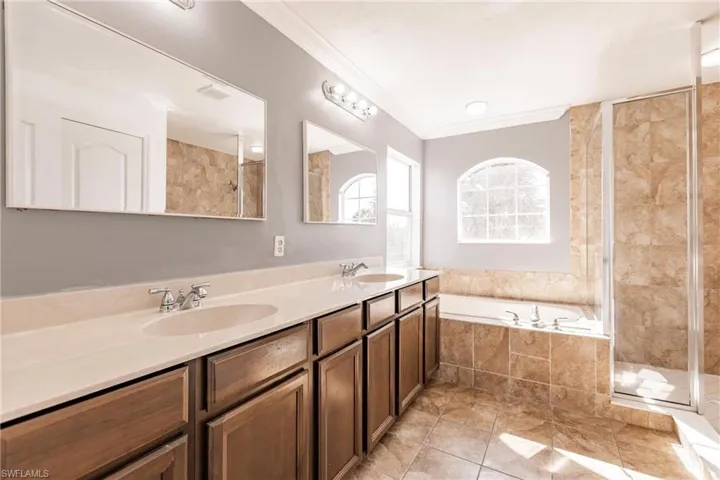 Bathroom with tile patterned floors, vanity, separate shower and tub, and crown molding