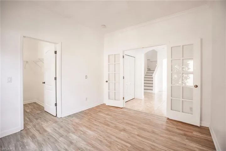 Empty room featuring french doors, crown molding, and light hardwood / wood-style flooring