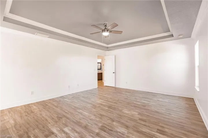 Unfurnished room with ceiling fan, wood-type flooring, crown molding, and a tray ceiling