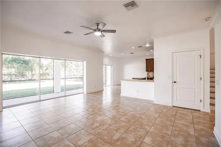Unfurnished living room featuring ceiling fan, light tile patterned floors, and ornamental molding