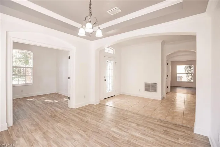 Foyer entrance with light wood-type flooring, an inviting chandelier, and crown molding