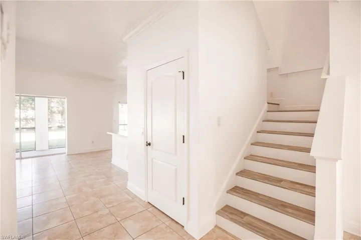 Stairs featuring tile patterned floors and crown molding