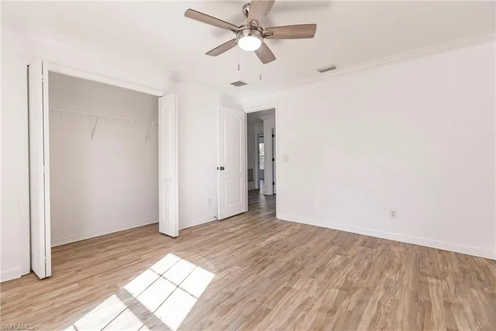 Unfurnished bedroom featuring light hardwood / wood-style floors, ceiling fan, and ornamental molding