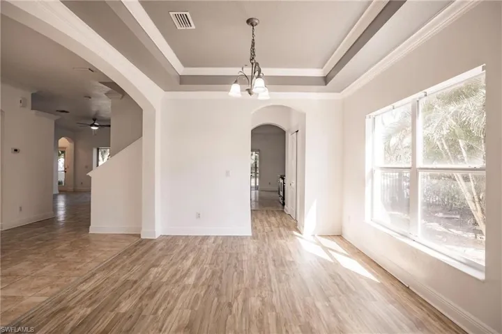 Spare room with ceiling fan with notable chandelier, wood-type flooring, and ornamental molding