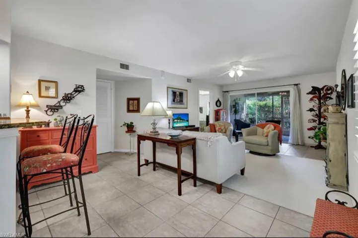 Living area featuring light tile patterned flooring, visible vents, and ceiling fan