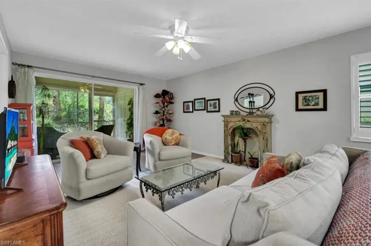 Living area featuring a ceiling fan, carpet, and a healthy amount of sunlight