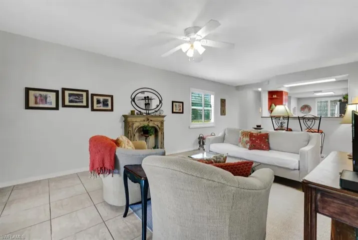 Living area with a ceiling fan, baseboards, a fireplace, and light tile patterned floors