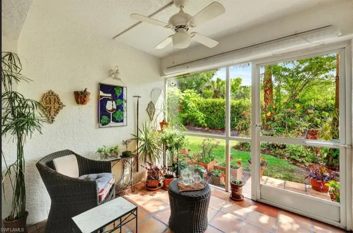 Sunroom / solarium with a textured wall, ceiling fan, and tile patterned floors