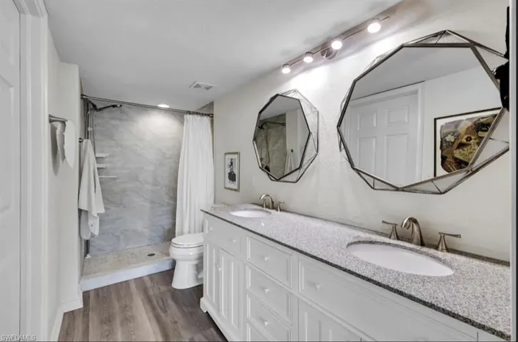 Full bathroom featuring toilet, a sink, visible vents, and double vanity