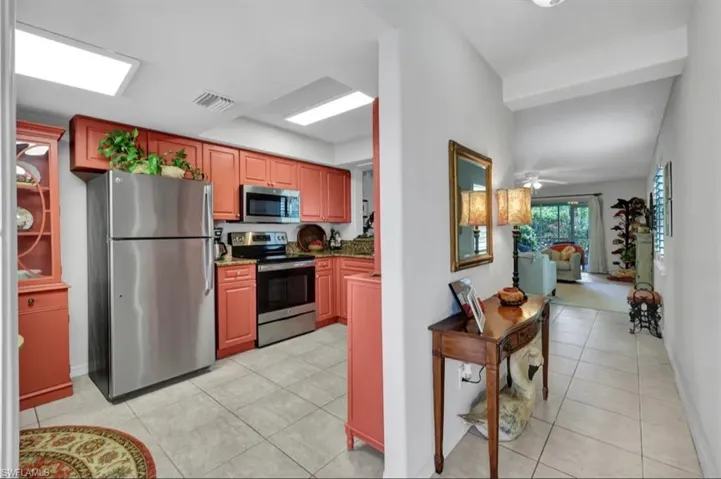 Kitchen with light stone counters, light tile patterned floors, ceiling fan, stainless steel appliances, and visible vents
