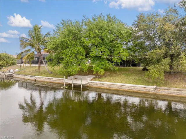 View of dock with a lawn and a water view