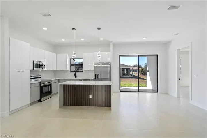 Kitchen featuring a kitchen island, pendant lighting, appliances with stainless steel finishes, healthy amount of natural light, and recessed lighting
