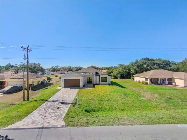 View of front of property featuring a front yard, decorative driveway, an attached garage, and a residential view