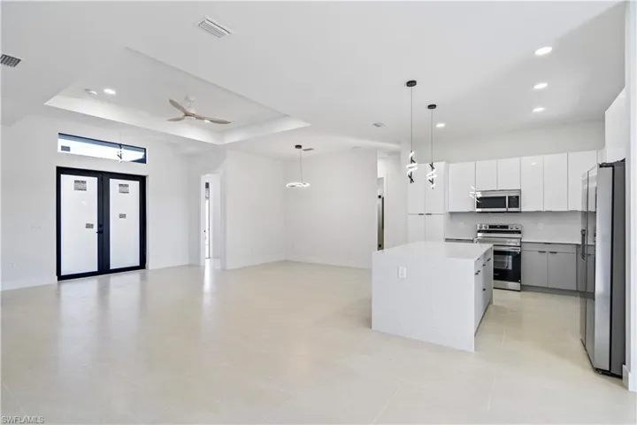 Kitchen featuring decorative light fixtures, appliances with stainless steel finishes, white cabinetry, open floor plan, and modern cabinets