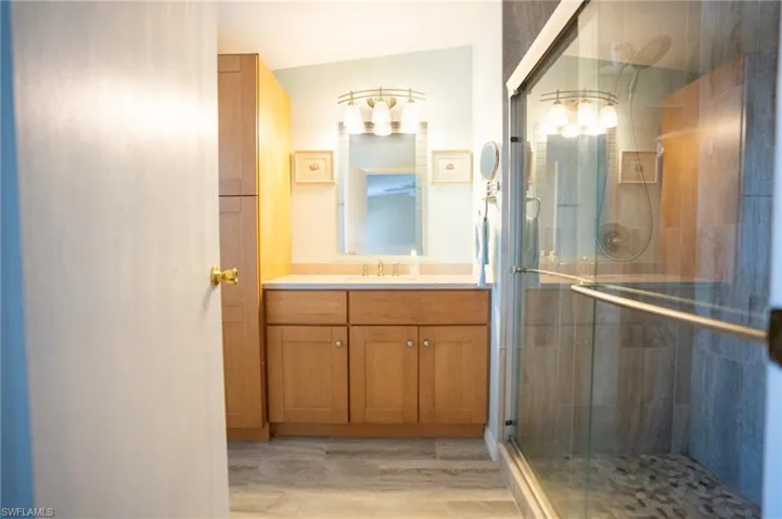 Full bathroom featuring vanity, a stall shower, and wood finished floors