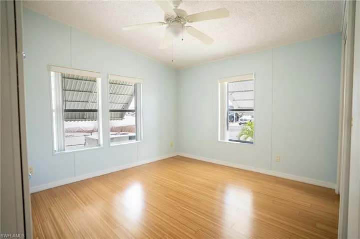 Unfurnished room featuring vaulted ceiling, a textured ceiling, light wood-type flooring, and ceiling fan