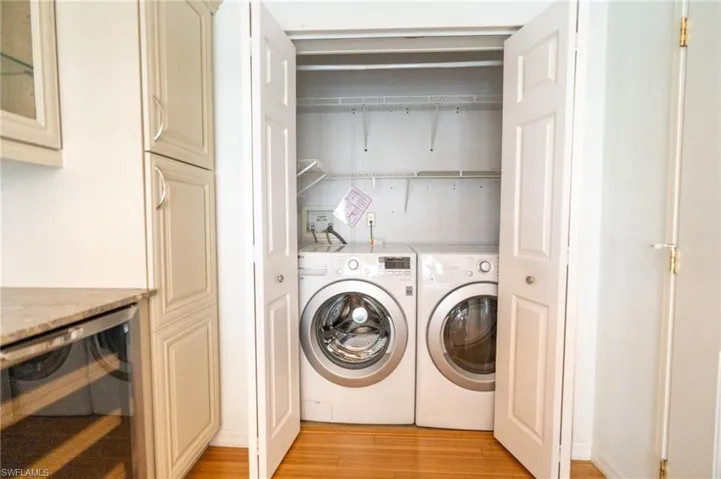 Laundry room with wine cooler, light wood-type flooring, and washer and clothes dryer
