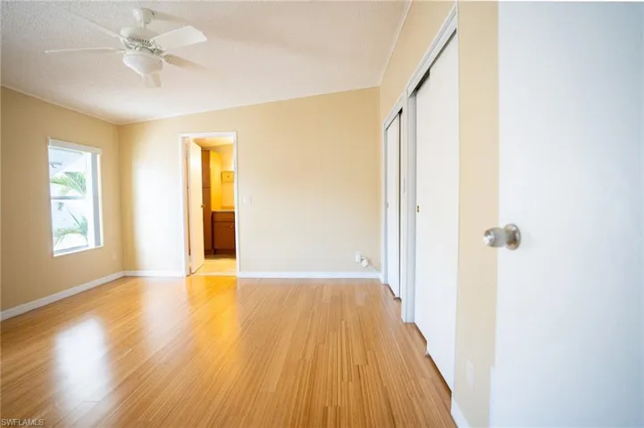 Unfurnished bedroom with light wood-type flooring, a closet, a textured ceiling, ensuite bathroom, and a ceiling fan