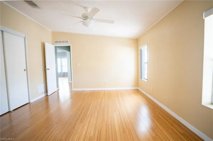 Unfurnished bedroom featuring light wood-style flooring, a textured ceiling, ornamental molding, a closet, and ceiling fan