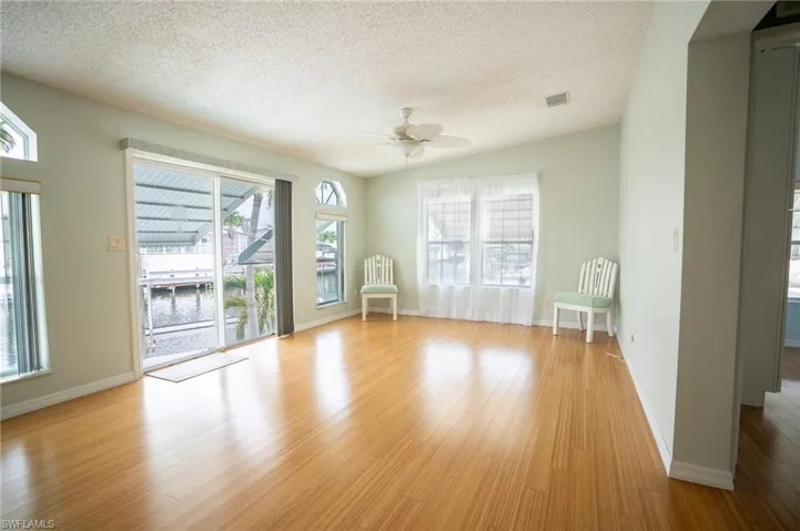 Empty room featuring a textured ceiling, a ceiling fan, light wood-style flooring, and a water view