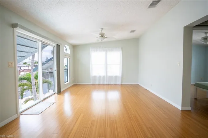 Empty room with ceiling fan, a textured ceiling, plenty of natural light, and light wood-style floors